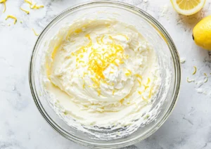 Cream cheese, sugar, and lemon zest in a bowl before mixing cheesecake batter